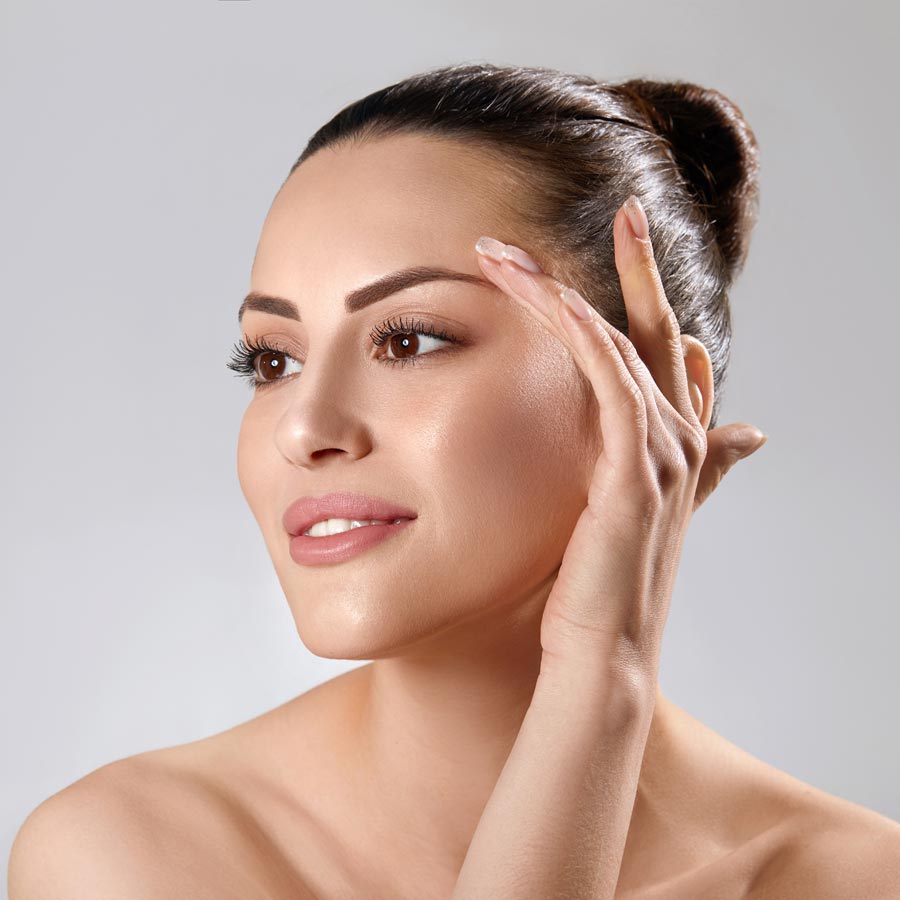 Beautiful young woman with clean perfect skin. Portrait of beauty model with natural nude make up and touching her face. Spa, skincare and wellness.