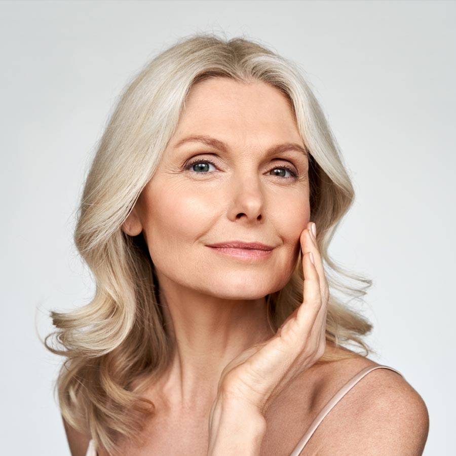 Beautiful gorgeous 50s mid aged mature woman looking at camera isolated on white. Mature old lady close up portrait.