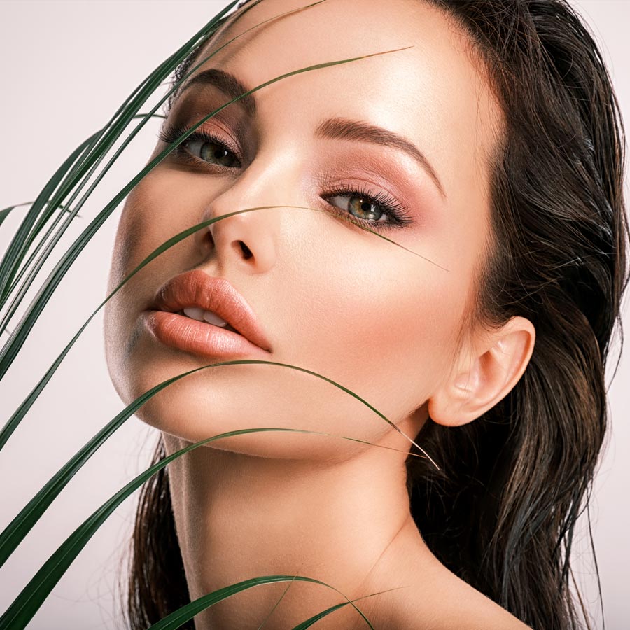 Young beautiful woman with green leaves near face and body. Skin care beauty treatments concept.